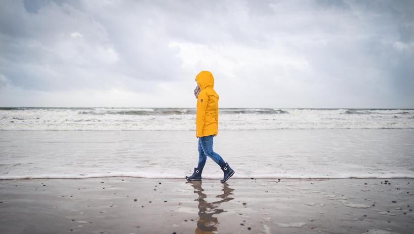 Spaziergänger in gelber Regenjacke am Strand von Blåvand an der Dänischen Nordsee