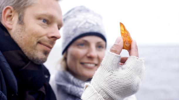 Een stel houdt gevonden amber omhoog op het strand in Denemarken