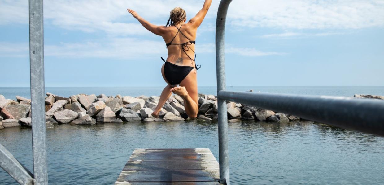 Person jumping in water at Svaneke harbour in Bornholm