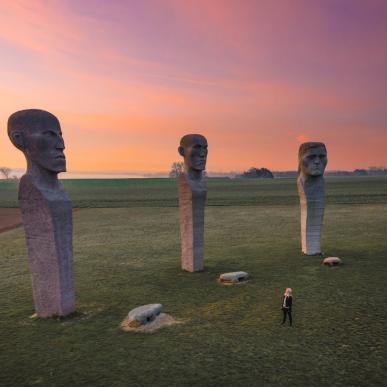 Person looking at stone sculptures Dodekalitten during sunset on Lolland-Falster, Denmark