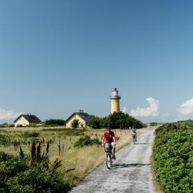 Fietsers passeren de Omø Fyr vuurtoren op het Deense eiland Omø