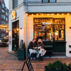 Et par sitter på en benk utenfor en kafe i København på vinteren